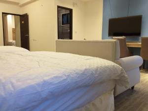 a bedroom with a white bed and a flat screen tv at Mesin-inn in Magong