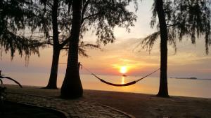 eine Hängematte zwischen zwei Bäumen am Strand bei Sonnenuntergang in der Unterkunft Marjoly Beach Resort in Teluk Bakau