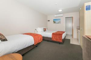 a hotel room with two beds and a television at Bella Vista Motel Lake Wanaka in Wanaka