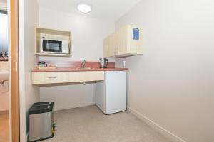 a small kitchen with a sink and a microwave at Bella Vista Motel Lake Wanaka in Wanaka