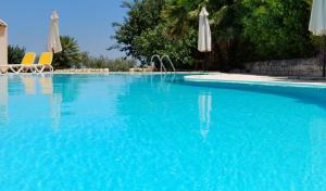a large blue swimming pool with chairs and umbrellas at Hotel Miralago in Tremosine Sul Garda