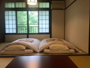 uma cama grande num quarto com duas janelas em Hakone Onsen Yuyado Yamanoshou em Hakone