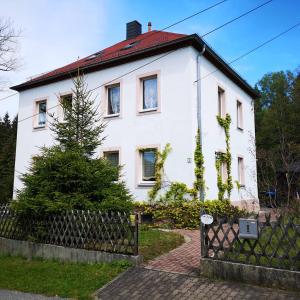 a white house with a fence in front of it at Ferienwohnung am Wald in Tharandt