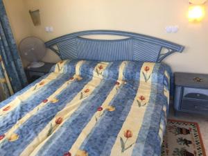 un letto con una trapunta blu e gialla con sopra dei fiori di villa (3 bed and 2 bath) in the Oliva Nova Golf&Beach resort a Oliva