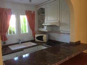 eine Küche mit weißen Schränken, einer Spüle und einer Mikrowelle in der Unterkunft villa (3 bed and 2 bath) in the Oliva Nova Golf&Beach resort in Oliva