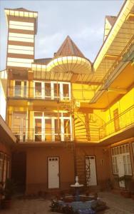 a large yellow building with a porch and a balcony at Inn Sogdiana in Panjakent
