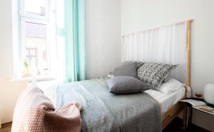 a bedroom with a bed with pillows and a window at Apartamenty KDN in Bielsko-Biała