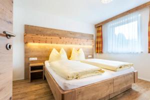 a bedroom with a large bed with a wooden headboard at Pension Ahorn in Saalbach Hinterglemm