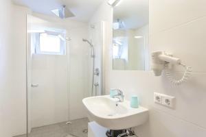a white bathroom with a sink and a shower at Pension Ahorn in Saalbach Hinterglemm