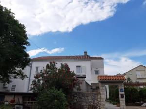 ein weißes Haus mit einem Steinzaun davor in der Unterkunft Apartments Knežević in Jadranovo