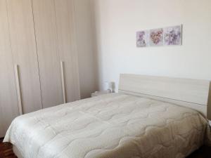 a white bedroom with a bed and a painting on the wall at A casa di Antonella in Biella