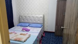 um pequeno quarto com uma cama branca com almofadas roxas e azuis em Elaine @ Home Stay em Kota Kinabalu