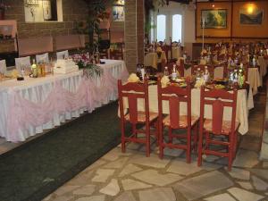 ein Esszimmer mit Tischen, weißen Tischdecken und Stühlen in der Unterkunft Kestenite Family Hotel in Samokow