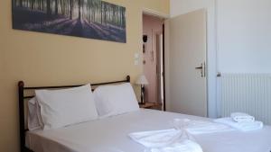1 dormitorio con cama blanca y almohadas blancas en Katerina Apartments, en Kalamata