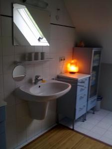 a bathroom with a sink and a mirror and a light at Pension Eltmann in Eltmann