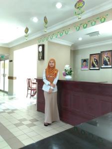 a woman standing next to a counter in a lobby at Hotel Seri Malaysia Mersing in Mersing