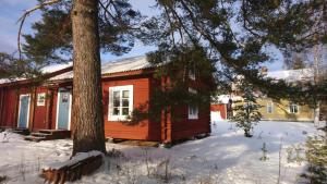 una cabaña roja en la nieve con un árbol en Soldattorpet Sands en Leksand