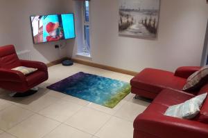 a living room with two red couches and a television at Cosy Castlerock Beside Beach Golf Course and Pub in Castlerock