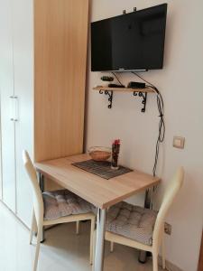 a table with two chairs and a television on a wall at Studio Apartman Irena1 in Bijela