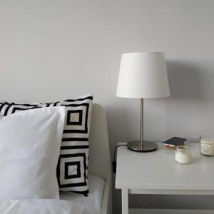 a bed with a table with a lamp and a pillow at White Almond Apartment in Budapest