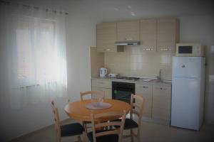 cocina con mesa, sillas y nevera blanca en Apartment Donat, en Zadar