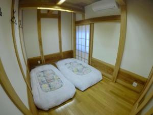 Duas camas num pequeno quarto com pisos em madeira em Narita Sando Guesthouse em Narita