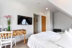 a white bedroom with a bed and a desk at Spicīte in Ventspils +34 photos