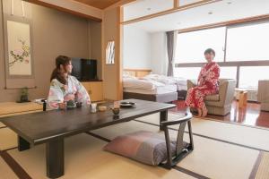 zwei Frauen in einem Wohnzimmer mit einem Tisch in der Unterkunft Yuzawa Grand Hotel in Yuzawa