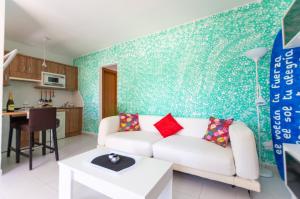 a living room with a white couch and a green wall at PoolViewZen in Corralejo