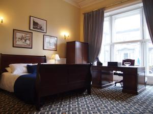 Schlafzimmer mit einem Bett, einem Schreibtisch und einem Fenster in der Unterkunft Thistle Hotel in Edinburgh
