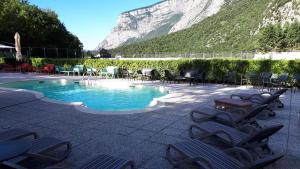 einem Pool mit Stühlen und einem Berg im Hintergrund in der Unterkunft Hotel Ciclamino in Pietramurata