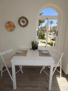 een witte eettafel met 2 stoelen en een raam bij Apartment La Isla Bonita in Jávea