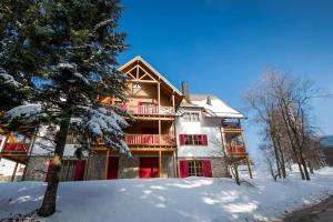 a house with red doors in the snow at Bolfenk lodge apartment in Pohorje