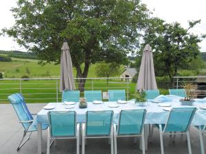 een blauwe tafel met blauwe stoelen en parasols bij Chez Basile in Oizy