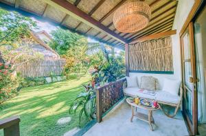 a porch with a chair and a view of a garden at Mule Malu Tropical Stay in Uluwatu