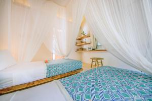 a bedroom with a canopy bed with white curtains at Mule Malu Tropical Stay in Uluwatu