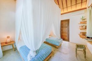 a bedroom with two beds and a curtain at Mule Malu Tropical Stay in Uluwatu