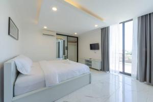a white bedroom with a bed and a large window at LY Residence Suite & Apartment in Siem Reap