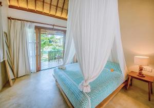 a bedroom with a bed with a mosquito net at Mule Malu Tropical Stay in Uluwatu