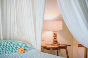 a bedroom with a bed and a table with a lamp at Mule Malu Tropical Stay in Uluwatu