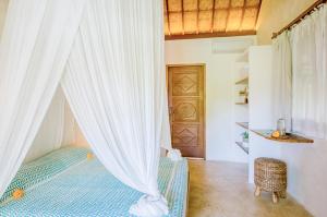 a bedroom with a bed with curtains and a door at Mule Malu Tropical Stay in Uluwatu