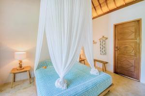 a bedroom with a bed with curtains and a door at Mule Malu Tropical Stay in Uluwatu
