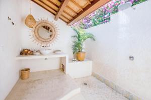 a bathroom with a mirror on the wall and a plant at Mule Malu Tropical Stay in Uluwatu