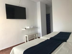 a bedroom with two beds and a flat screen tv at Hotel Playa San Cristóbal in Almuñécar