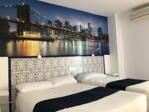 1 dormitorio con 2 camas y un gran mural de la ciudad en Hotel Playa San Cristóbal, en Almuñécar