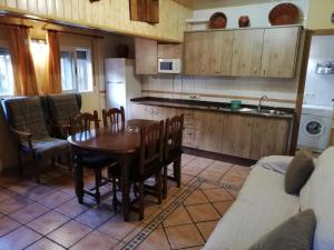 eine Küche mit einem Holztisch und Stühlen sowie eine Küche mit einer Küche in der Unterkunft Alojamientos Rurales Vado Ancho La Encina in Arroyo Frio