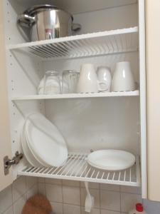 a kitchen pantry with white dishes and a sink at Huoneistohotelli Teekki in Muuruvesi