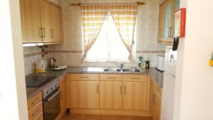 une cuisine avec des armoires en bois, un évier et une fenêtre dans l'établissement Casa do Mar, à Salema