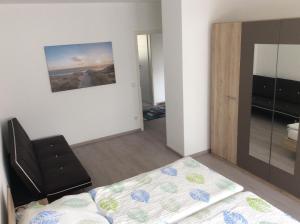 1 dormitorio con cama, silla y espejo en Apartment Perla, en Limburg an der Lahn