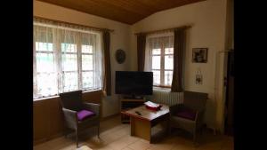 a living room with a table and chairs and a television at Horváth Apartmanház in Szigliget